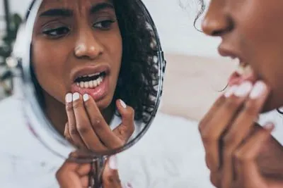 patient looking at her teeth in the mirror after having tooth pain