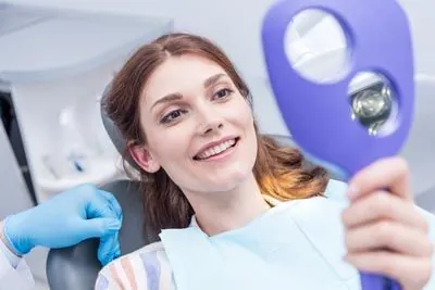patient looking in the mirror at the dentist after having her teeth cleaned